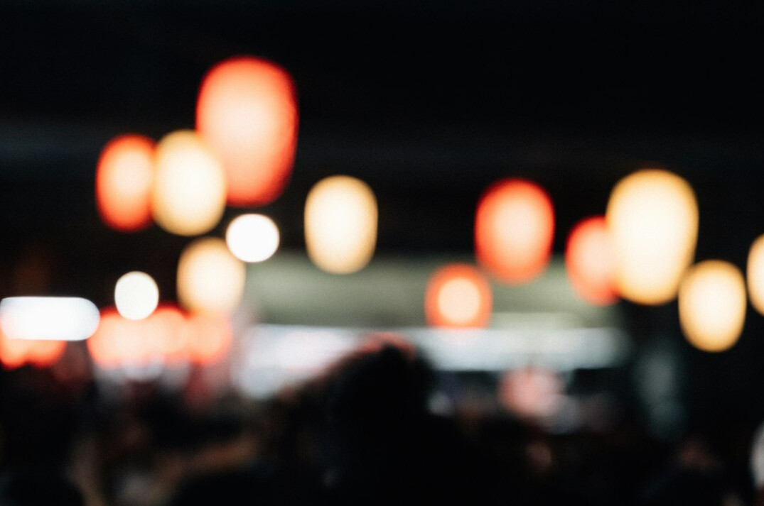 Blurred silhouettes of an audience watching a distant illuminated stage