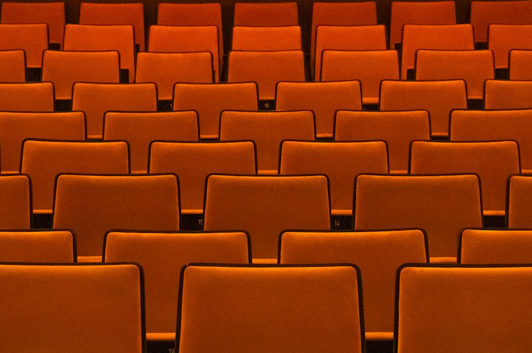 Rows of empty theatre seats lit by soft stage light